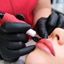 Beautician doing a lip makeup covered with cosmetic tattoo insurance