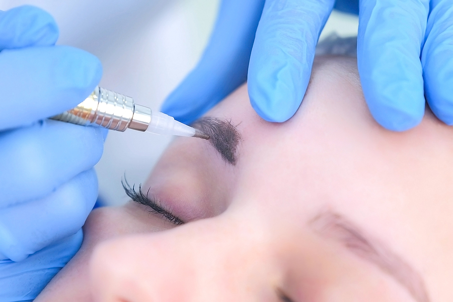 Cosmetologist doing eyebrows microblading procedure 